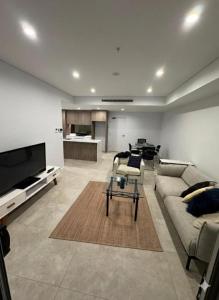a living room with a couch and a tv and a table at Cozy Suite in Schofields in Schofields