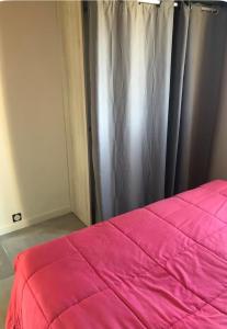 a bedroom with a pink bed and a curtain at Gîte Ruoms in Ruoms