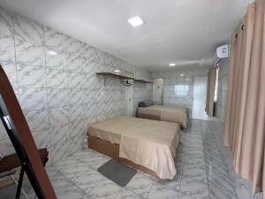 a bedroom with two beds and a tiled wall at Casa Beira Mar lha de Itamaracá in Itamaracá