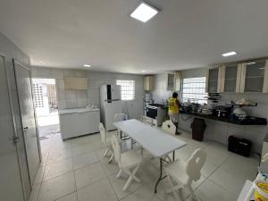 a woman in a kitchen with a table and chairs at Casa Beira Mar lha de Itamaracá in Itamaracá