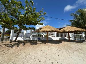 two straw umbrellas in front of a white building at Casa Beira Mar lha de Itamaracá in Itamaracá