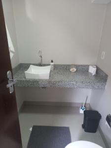 a bathroom counter with a sink and a toilet at Apartamento Centro 02 in Vilhena