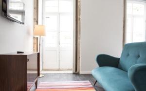 a living room with a blue couch and a television at Porto República Suites in Porto +3 photos