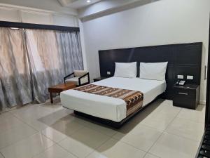 a bedroom with a large bed and a chair in it at Hotel Takia in Labasa
