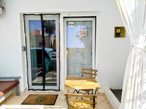 a porch with a wooden bench and a glass door at Studio Murdeira Side Beach, Eco Protected Bay, Pool 161B in Beirona