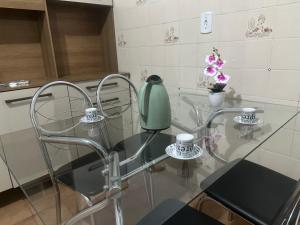 a glass table with chairs and a green vase on it at E Lindo Sobrado com 2 quartos em condomínio - Centro in Marília