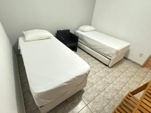 a room with two beds and a chair at E Lindo Sobrado com 2 quartos em condomínio - Centro in Marília