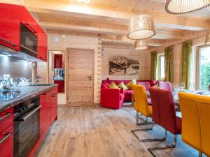 a kitchen and living room with red and yellow chairs at Adventure Lodge Kaprun in Kaprun
