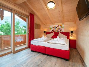 a red bed in a room with a large window at Adventure Lodge Kaprun in Kaprun