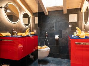 a bathroom with red cabinets and a toilet at Adventure Lodge Kaprun in Kaprun +18 photos