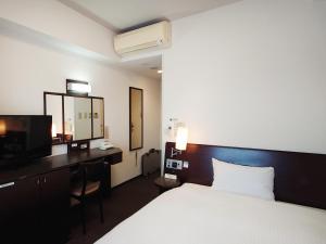a hotel room with a bed and a desk and a television at Hotel Route-Inn Yurihonjo in Yurihonjo