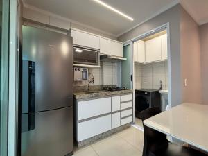 a kitchen with a stainless steel refrigerator and white cabinets at 01 Qt.| 2 Hosp. | Linda Vista | Jacuzzi Privativa in Goiânia