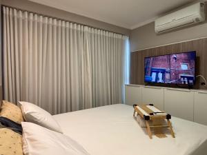 a bedroom with a large bed with a tv on the wall at 01 Qt.| 2 Hosp. | Linda Vista | Jacuzzi Privativa in Goiânia