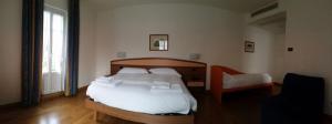 una camera da letto con un letto con lenzuola bianche e una finestra di Hotel Lario a Mezzegra