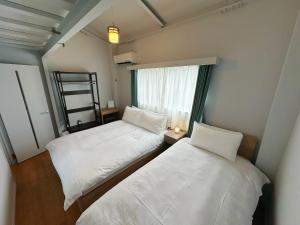 two beds in a small room with a window at HennaWatei in Osaka
