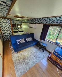 a living room with a blue couch and a bedroom at Ônibus Azul - Experiência de Hospedagem em Domingos Martins in Domingos Martins