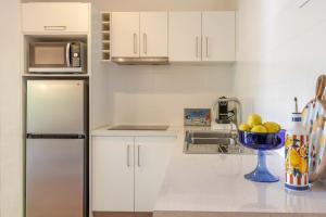 a kitchen with a refrigerator and a bowl of fruit at Let's Get Tropical, Located In The Heart Of Town, 2 King Beds, 2 Pools, 2 Bathrooms in Port Douglas