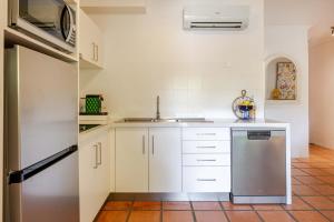 a kitchen with white cabinets and a stainless steel refrigerator at Let's Get Tropical, Located In The Heart Of Town, 2 King Beds, 2 Pools, 2 Bathrooms in Port Douglas