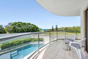 a balcony with a swimming pool and a chair on it at Whale Point in Yaroomba