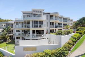 an apartment building with balconies and bushes at Whale Point in Yaroomba