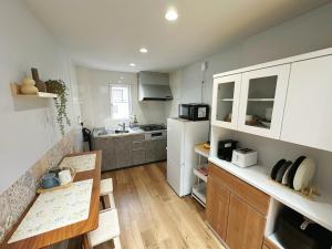 a small kitchen with a table and a white refrigerator at HennaWatei in Osaka
