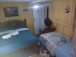 a bedroom with two beds and a table in it at Hospedagem coqueiros in Soure