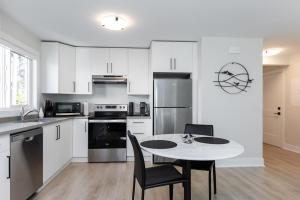a kitchen with white cabinets and a table and chairs at Cozy Corner on Trumpeter in Colwood