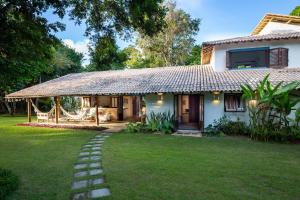 a house with a thatch roof and a grass yard at Casa Pini - Condomínio Altos de Trancoso, próxima ao Quadrado in Trancoso