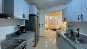 a kitchen with white cabinets and a sink and a couch at Apartamento San Pedro Colonial in San Pedro de Macorís