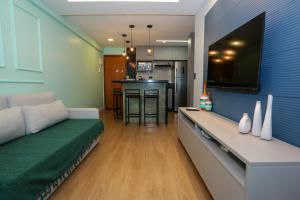 a living room with a couch and a tv on a wall at Flat Rosarinho - Confortável e Super Completo in Recife