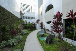 a garden with two benches and plants in front of a building at Flat Rosarinho - Confortável e Super Completo in Recife