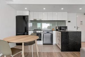 a kitchen with white cabinets and a wooden table at Proximity Waterfront Apartments in Redcliffe +107 photos