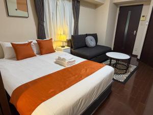 a hotel room with a large bed and a chair at BALCOM STAY Hiroshima Otemachi in Hiroshima