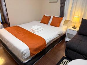 a bedroom with a bed with orange pillows and a chair at BALCOM STAY Hiroshima Otemachi in Hiroshima