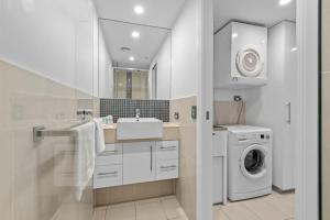 a white bathroom with a sink and a washing machine at Proximity Waterfront Apartments in Redcliffe