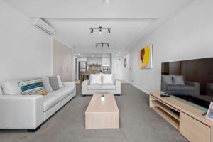a living room with two white couches and a table at Proximity Waterfront Apartments in Redcliffe