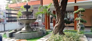 a fountain in front of a building with a tree at Edu HOTEL Y-SKANAM SYARIAH in Surabaya