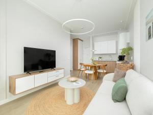 a living room with a white couch and a tv at Comfortable apartment, right on the beach in Niechorze