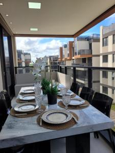 a table with plates and glasses on a balcony at Resort Cais Eco Residence in Ipojuca