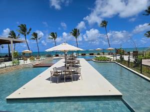 a swimming pool with tables and chairs and umbrellas at Resort Cais Eco Residence in Ipojuca