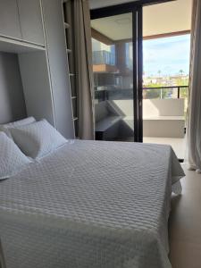 a bedroom with a white bed and a balcony at Resort Cais Eco Residence in Ipojuca