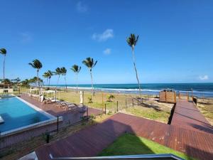 a view of a beach with palm trees and a swimming pool at Resort Cais Eco Residence in Ipojuca