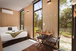 a bedroom with a bed and a table with chairs at Maroota Greens X by Tiny Away in Maroota