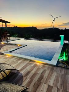 a swimming pool with a sunset in the background at Margarida 02 in Monte das Gameleiras