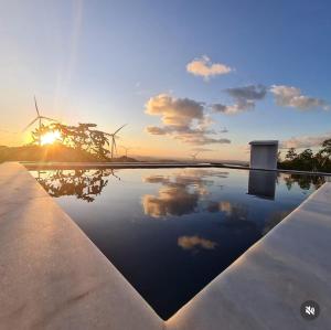 a pool with a sunset and windmills in the background at Margarida 02 in Monte das Gameleiras