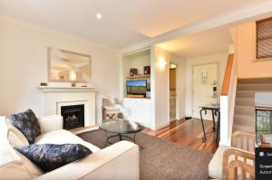 a living room with a white couch and a fireplace at Villa Rose with Free Wine Tasting Included in Pokolbin