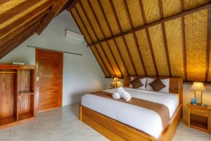 a bedroom with a bed and a wooden ceiling at La Rise Penida Cottage in Nusa Penida