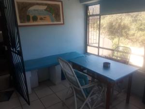 a blue table and chairs in a room with a window at Fishermen s Cave in Port St. Johns