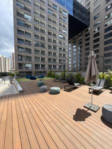 a wooden deck with an umbrella and chairs and benches at Almagah 227 - Studios de Alto Padrão no Tatuapé - SP in São Paulo
