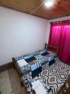 two beds in a room with a pink curtain at Complejo Indanna in San Rafael